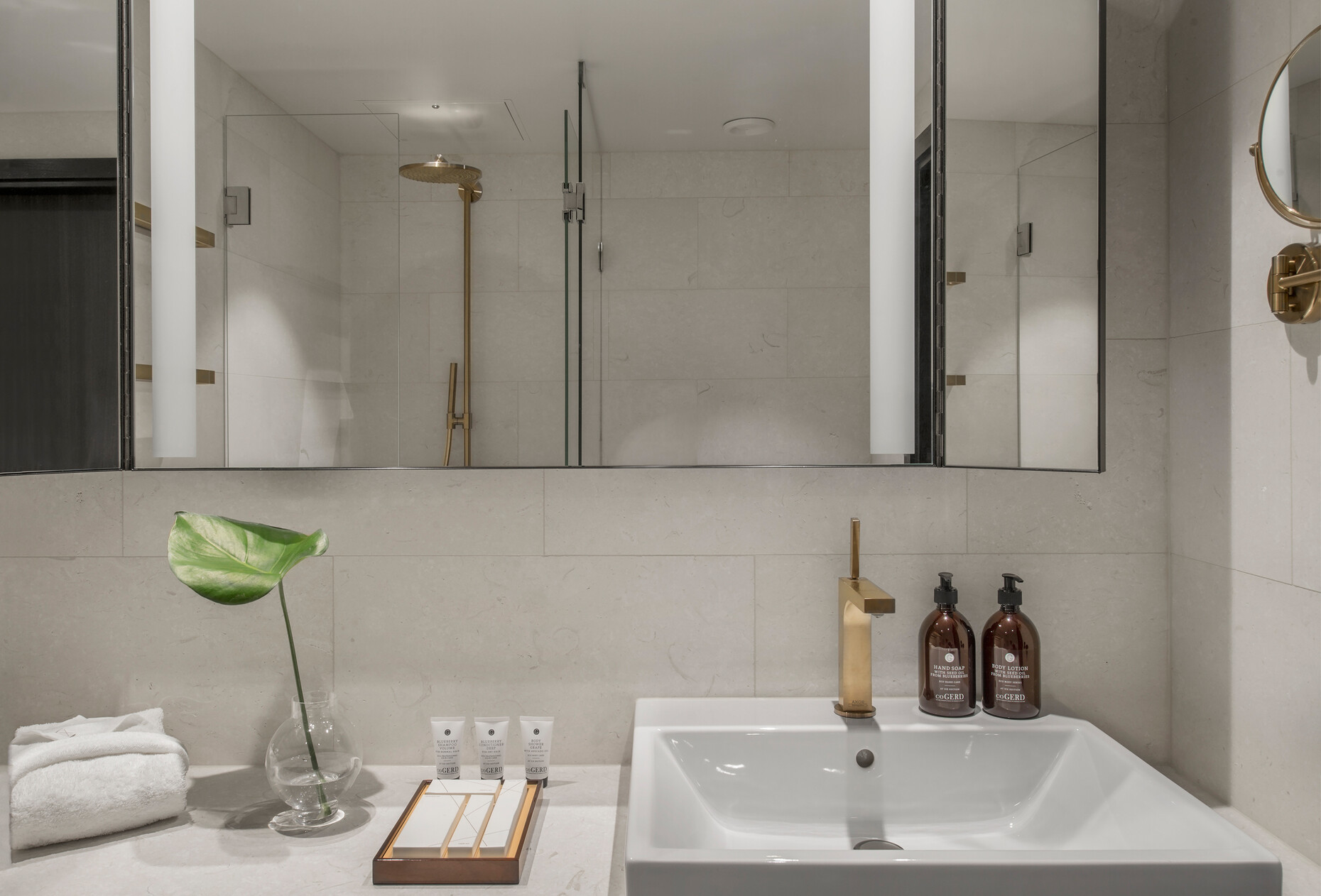 Die Armaturen und Brausen aus der Kollektion "Axor Citterio" setzen mit der Axor FinishPlus Oberfläche "Brushed Bronze" in den hellen Bädern die Akzente.