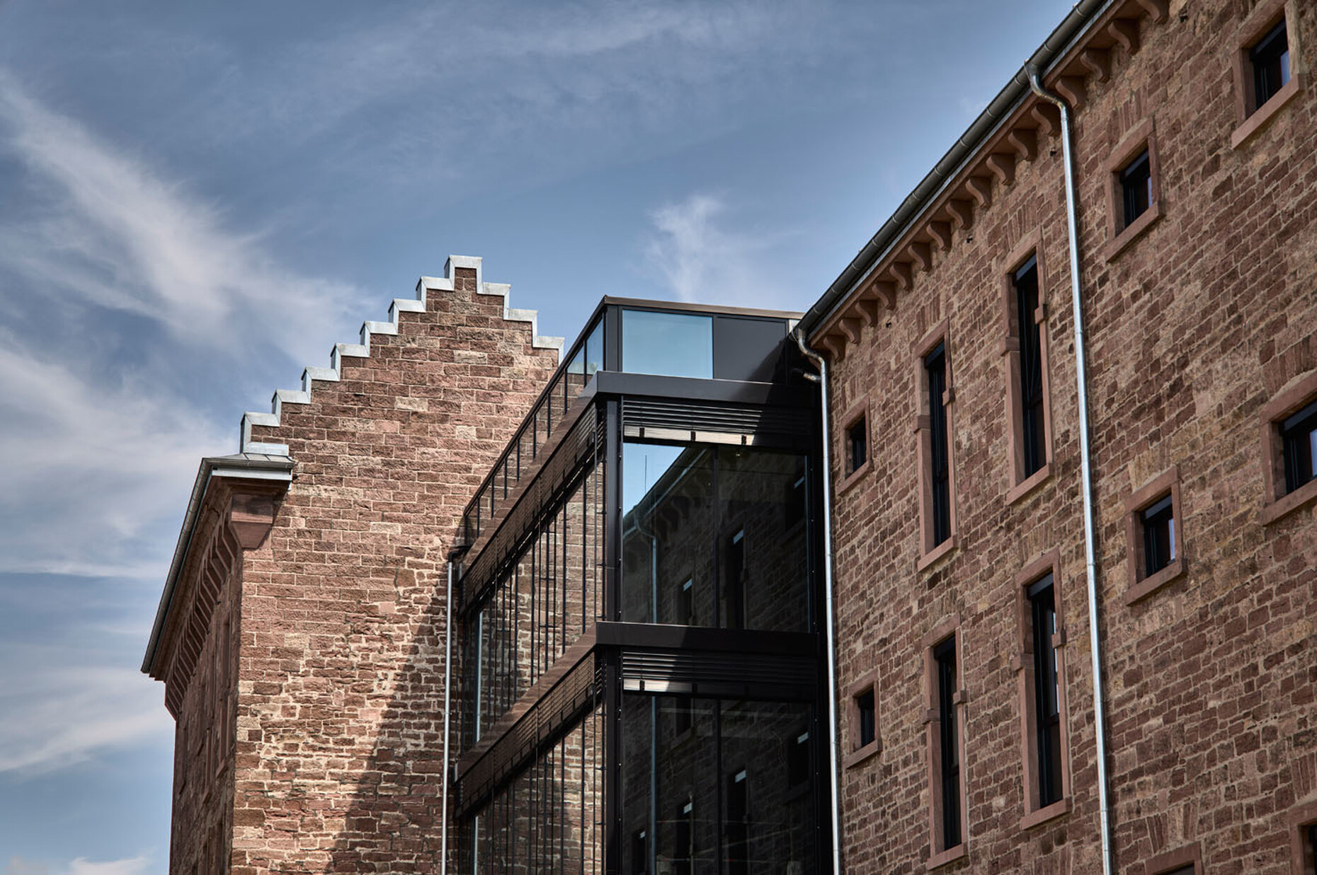 Die getrennten Teile des Gebäudekomplexes hat Architekt Jürgen Grossmann mit einem modernen Glaskubus verbunden.