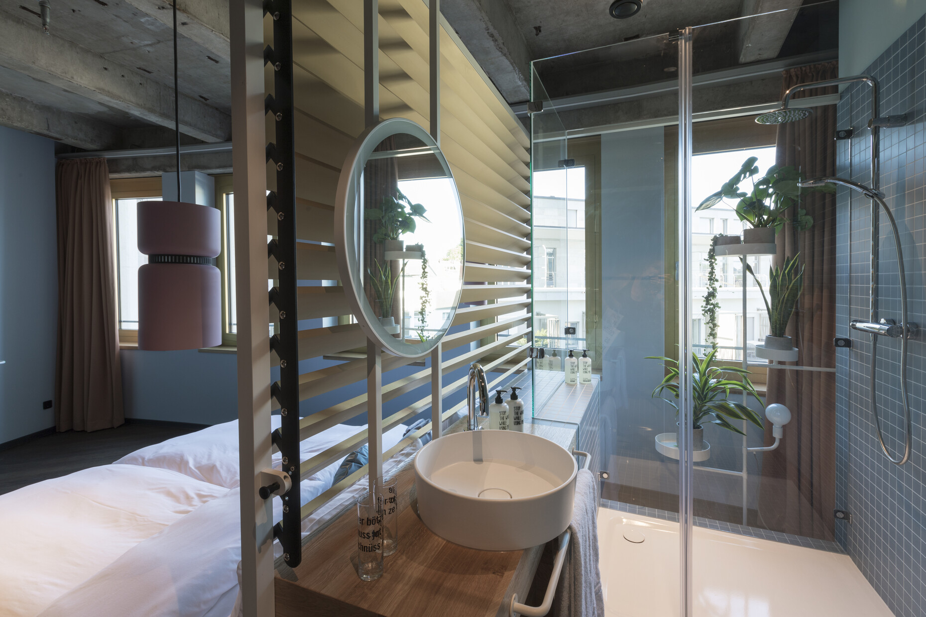 Nur Lamellen zwischen Bett und Bad: Im Hotel "The Circle" in Köln ist die Grenze zwischen Schlaf- und Sanitärbereich weitgehend aufgehoben. Das Waschbecken stammt aus der Kollektion "Kartell by Laufen".