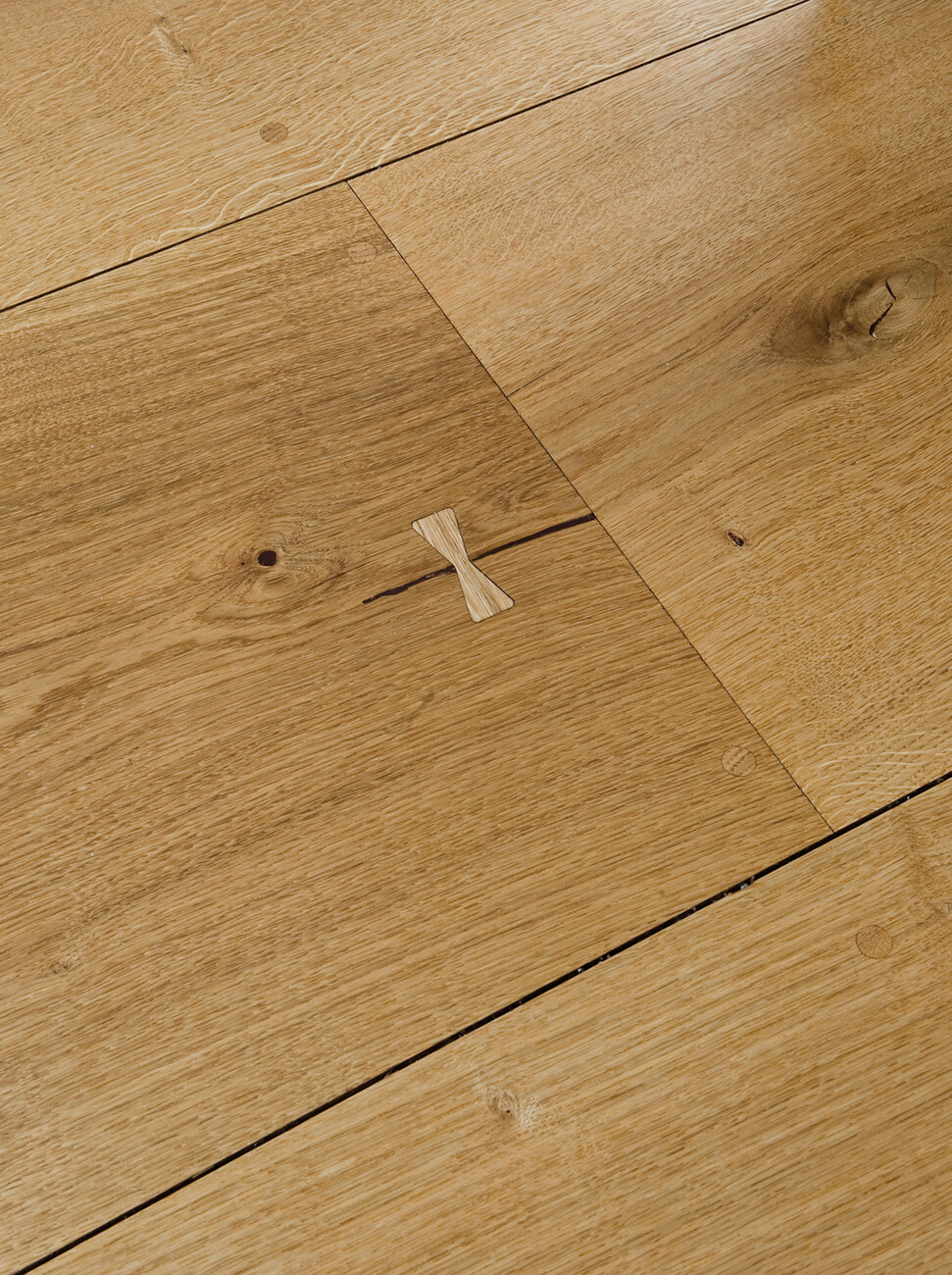The natural cracks in the oak planks have been preserved and are fixed with loop-shaped inserts.