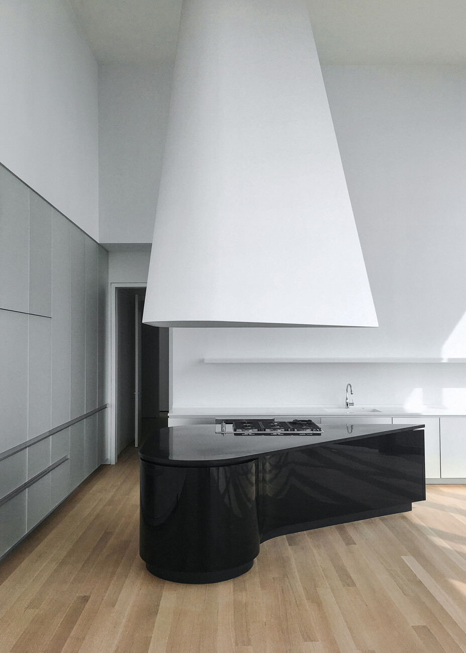 With their fluid shapes the glossy black kitchen blocks with granite countertops fit the layout of the space perfectly.