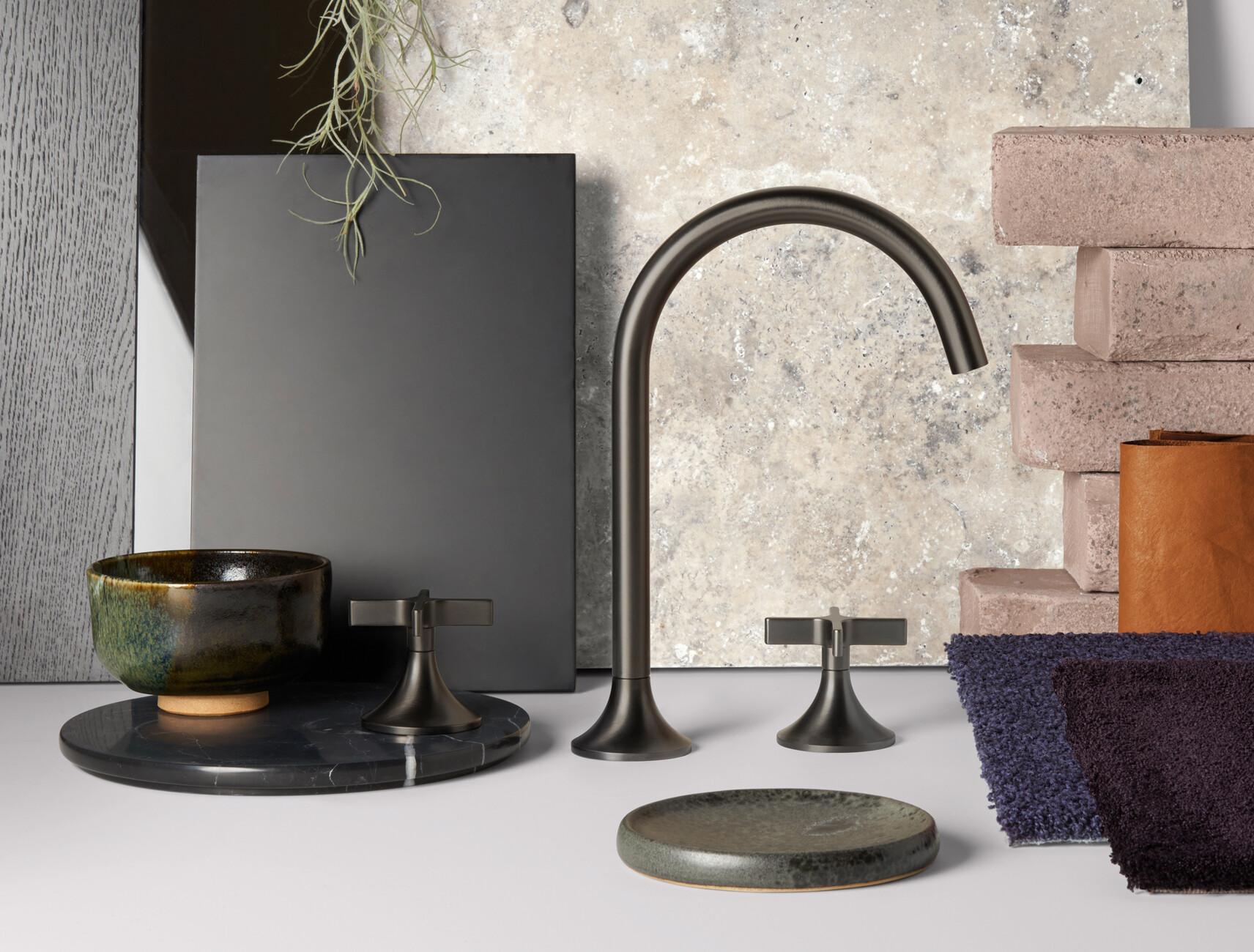 Rafael de Cárdenas kombinierte die "Vaia"-Armatur in Dark Platinum matt, Acrylstein, Rauchglas, Moos, Marmor, Mooseiche sowie cognacfarbenem Leder und einem violetten Teppichboden.