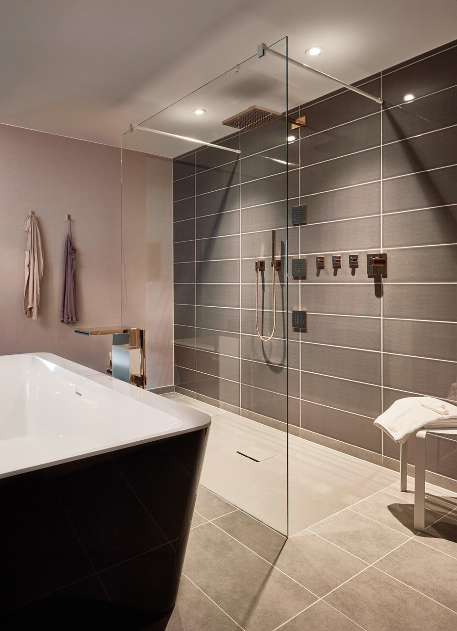 Flächen in sanftem Nude schaffen in farblichen Kombination mit matten Grautönen und sattem Schwarz eine angenehme Atmosphäre im Bad.