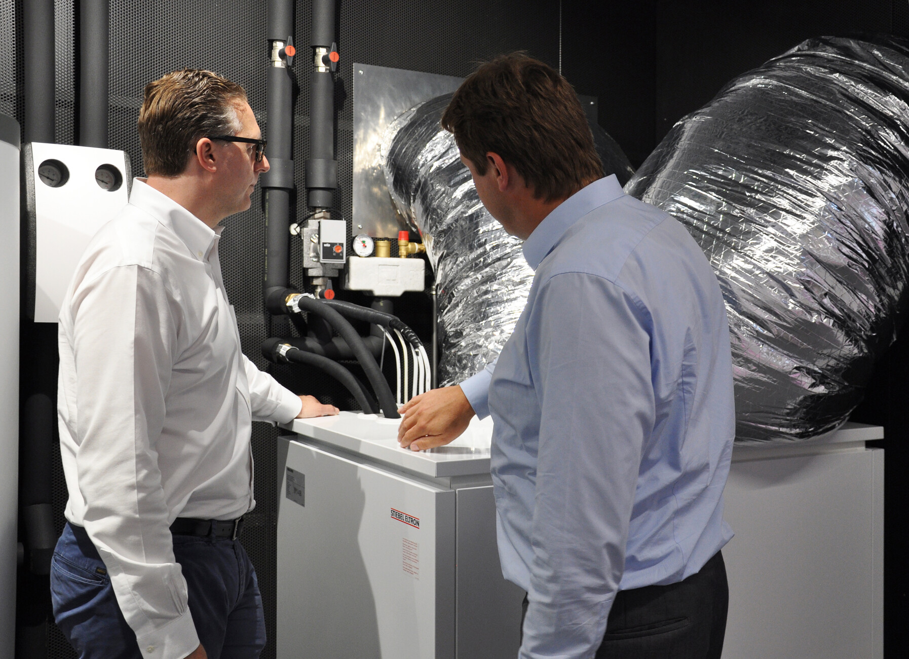 Die Funktionsweise der Luft-Wasser-Wärmepumpe in der Wärmepumpen-Themenwelt kann im echten Betrieb unter die Lupe genommen werden. Henning Schulz (re.), Presseansprechpartner bei Stiebel Eltron, zeigt Robert Volhard, Stylepark, die Abläufe des Geräts im Detail.