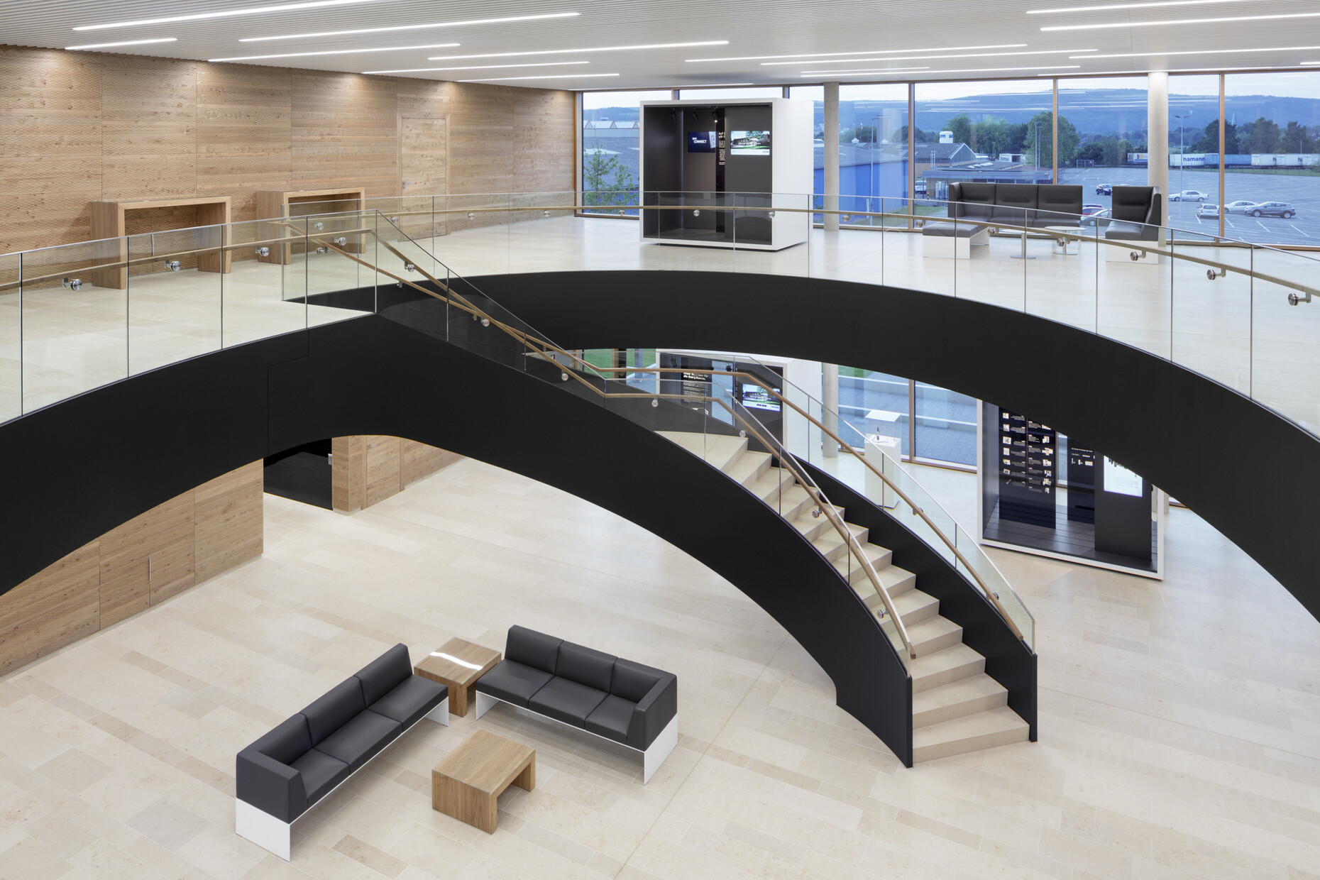 Schwungvoll: Vom Foyer aus führt eine gekurvte Treppe in das obere Stockwerk. Der Empfangsbereich bietet viele Möglichkeiten für Begegnungen und Kommunikation.